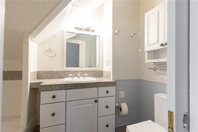 a bathroom with a granite countertop sink mirror and toilet