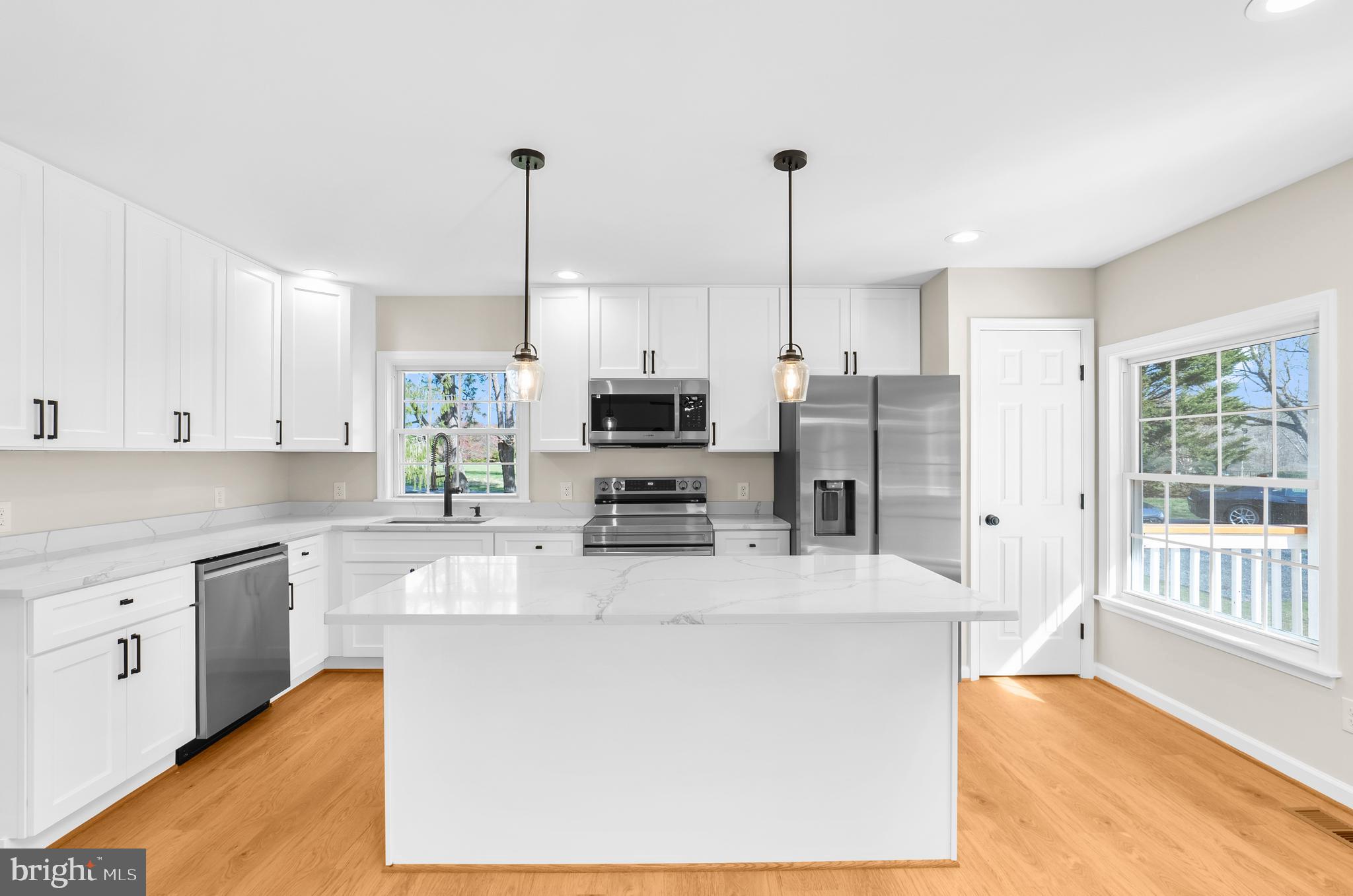 5485 Solomons Island Road Lothian, MD 20711 - Photo 48 of 64 a kitchen with stainless steel appliances kitchen island granite countertop a refrigerator a stove top oven a sink and dishwasher with wooden floor