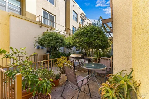 a patio with table and chairs and potted plants