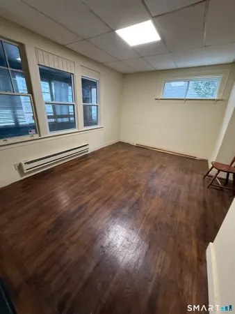 a view of an empty room with a window and wooden floor