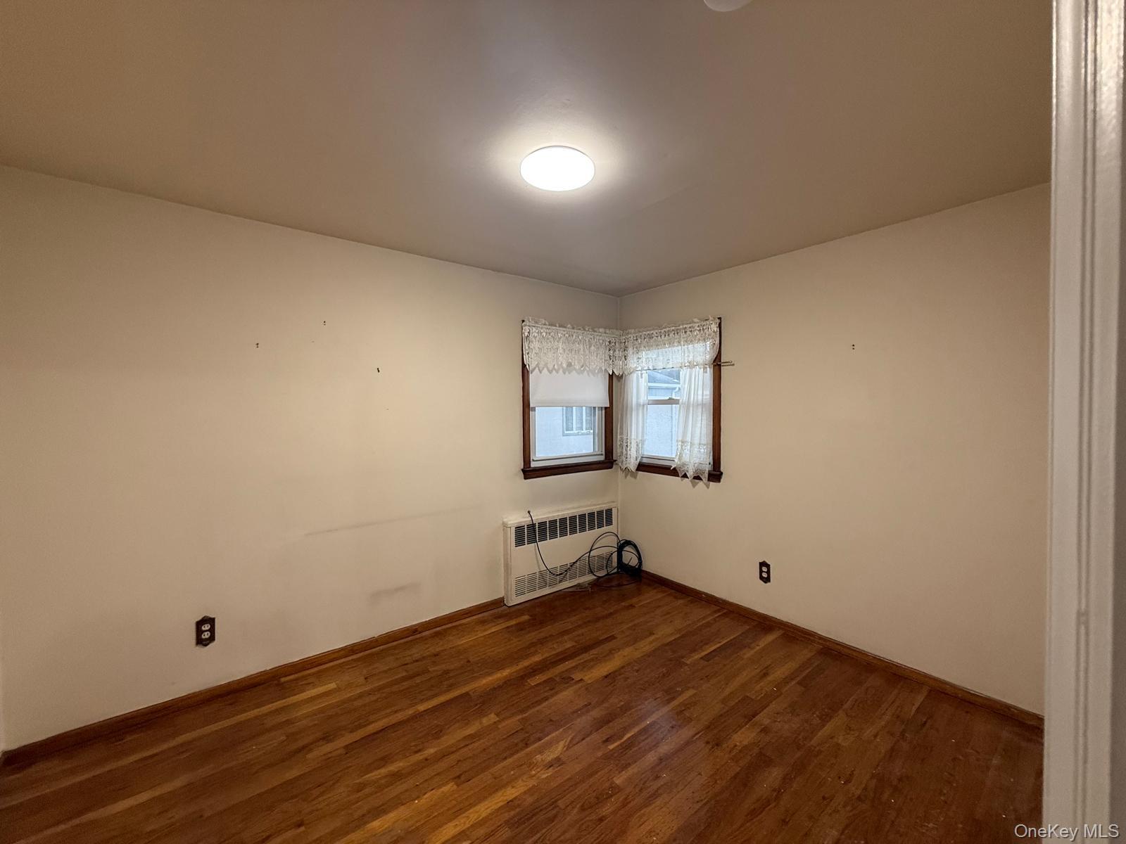 110 Evergreen Avenue, Unit 2 Lynbrook, NY 11563 - Photo 13 of 18 an empty room with wooden floor and windows