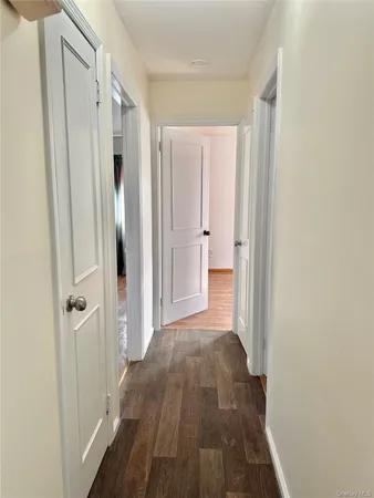 a view of a hallway with wooden floor and a bathroom
