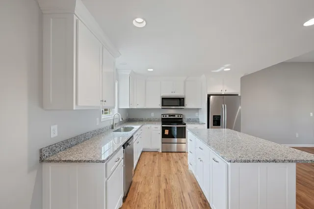 a kitchen with granite countertop a sink a counter top space stainless steel appliances and cabinets