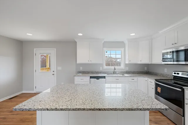 a kitchen with stainless steel appliances granite countertop a sink stove and cabinets
