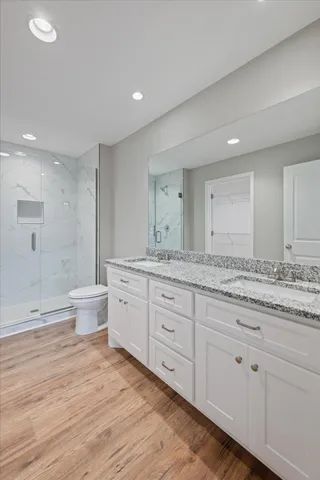 a spacious bathroom with a granite countertop double vanity sink a mirror and a toilet