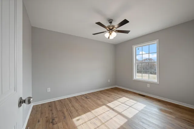 a view of empty room with wooden floor and window