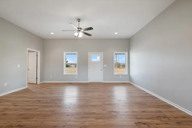 a view of empty room with wooden floor and fan