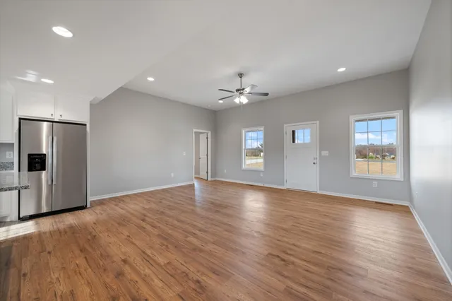 a view of an empty room with window and wooden floor