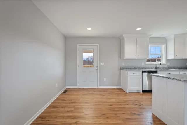 a big room with kitchen island granite countertop cabinets and wooden floor