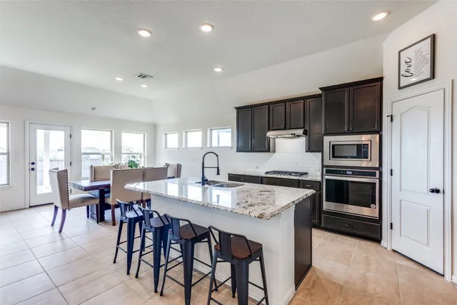 a kitchen with kitchen island granite countertop wooden cabinets a stove a dining table and chairs