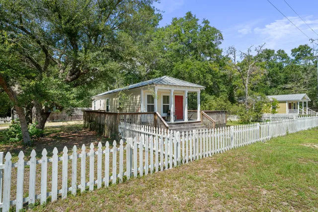 a view of a house with a small yard and a large tree