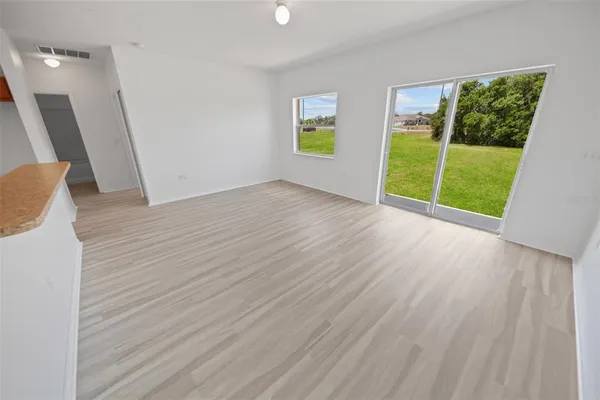 a view of an empty room with a window and wooden floor