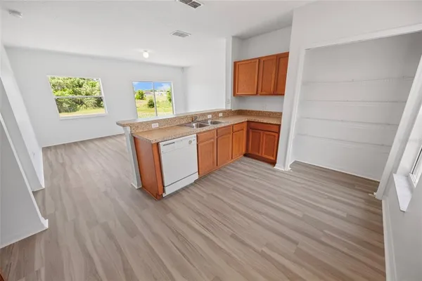 a kitchen with stainless steel appliances granite countertop a stove a sink and a refrigerator with wooden floor