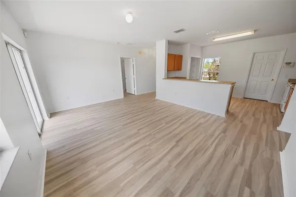 a view of a big room with wooden floor and a kitchen