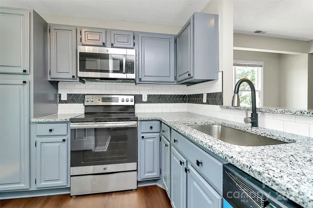 a kitchen with granite countertop a stove microwave and sink