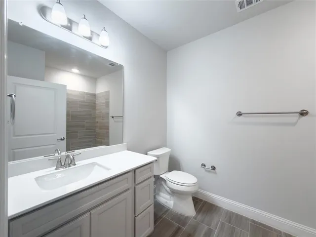 a bathroom with a granite countertop sink a toilet and a mirror