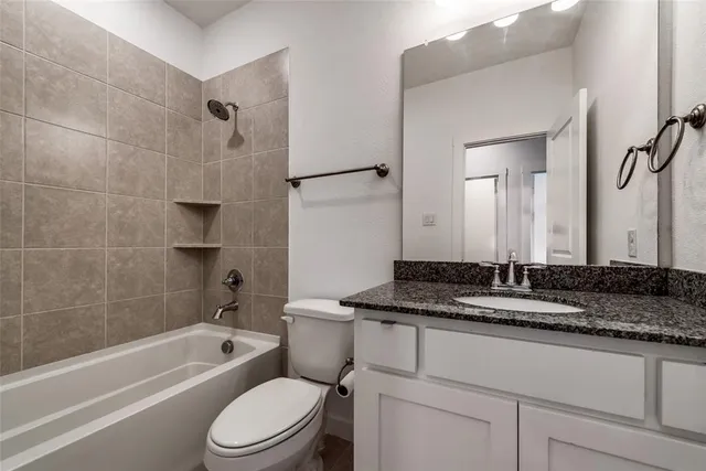 a bathroom with a granite countertop sink toilet mirror and bathtub