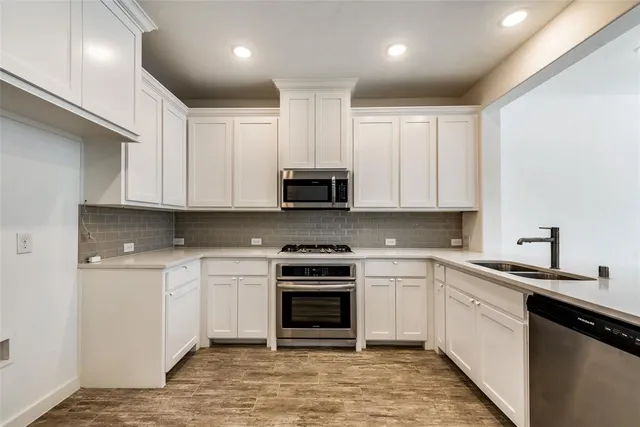 a kitchen with granite countertop white cabinets and stainless steel appliances