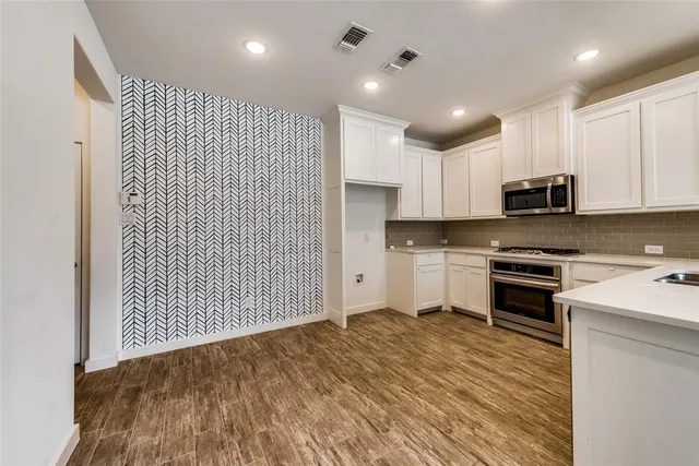 a kitchen with stainless steel appliances granite countertop a stove a sink and a microwave