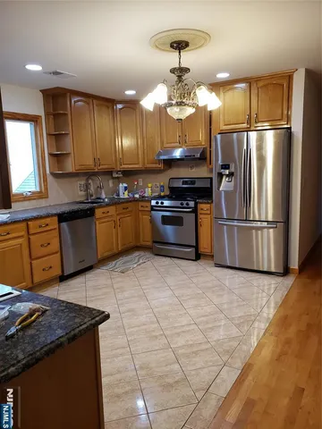 a kitchen with stainless steel appliances granite countertop a refrigerator a stove a sink a microwave and island