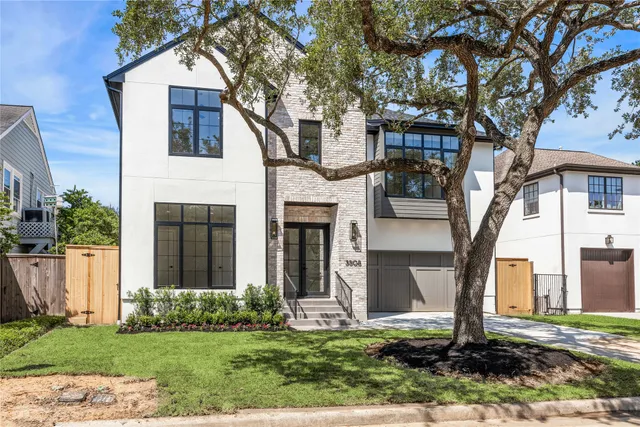 a front view of a house with a yard and large tree
