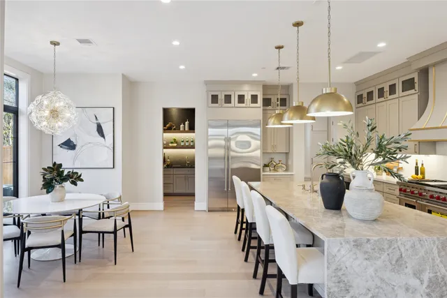 a kitchen with stainless steel appliances kitchen island granite countertop a dining table chairs and white cabinets