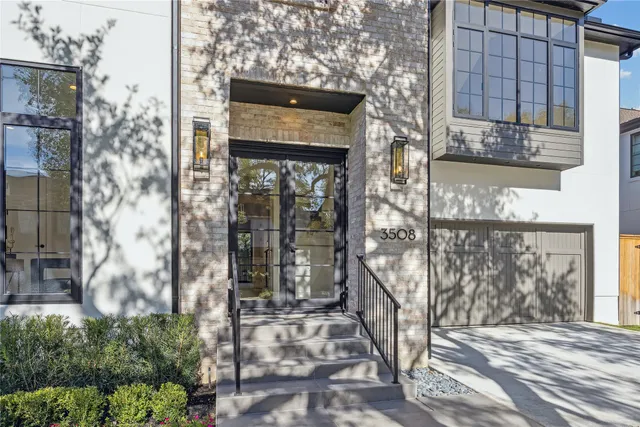 a view of a brick house with large windows and tree