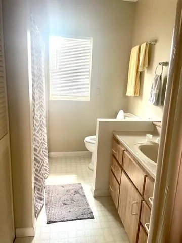a bathroom with a sink a toilet a window and vanity