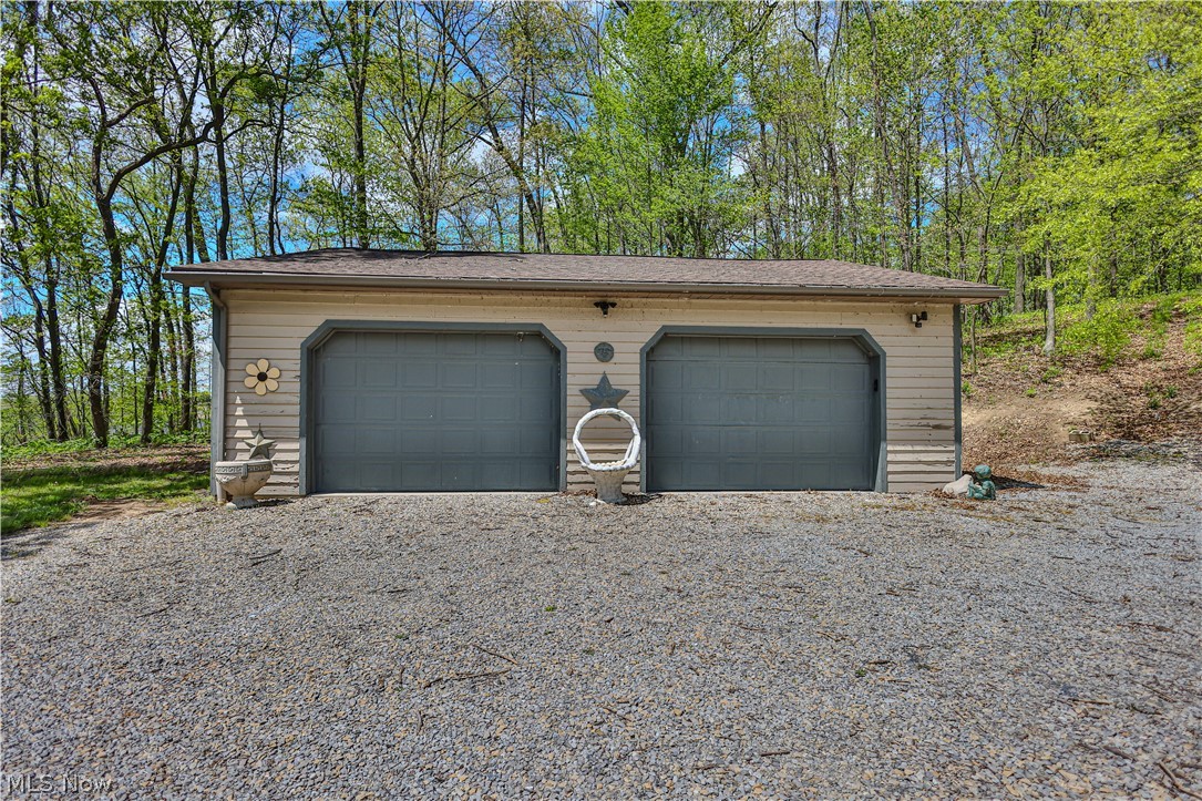 11154 Johnsford Road Southwest Beach City, OH 44608 - Photo 7 of 50 Two-car garage with tan siding, dual grey overhead doors, and exterior lighting fixtures