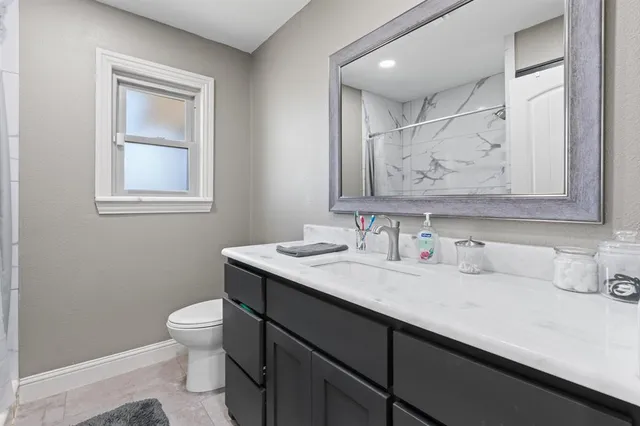 a bathroom with a granite countertop sink mirror vanity and toilet