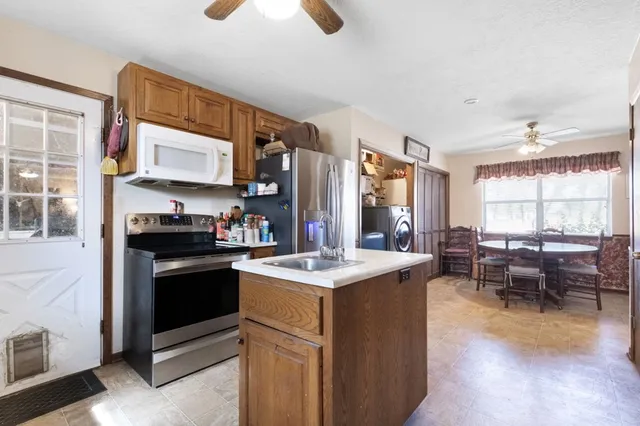 a kitchen with stainless steel appliances granite countertop a stove top oven a sink dishwasher a dining table and chairs with wooden floor