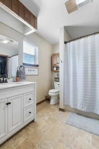 a spacious bathroom with a double vanity sink a mirror and a toilet