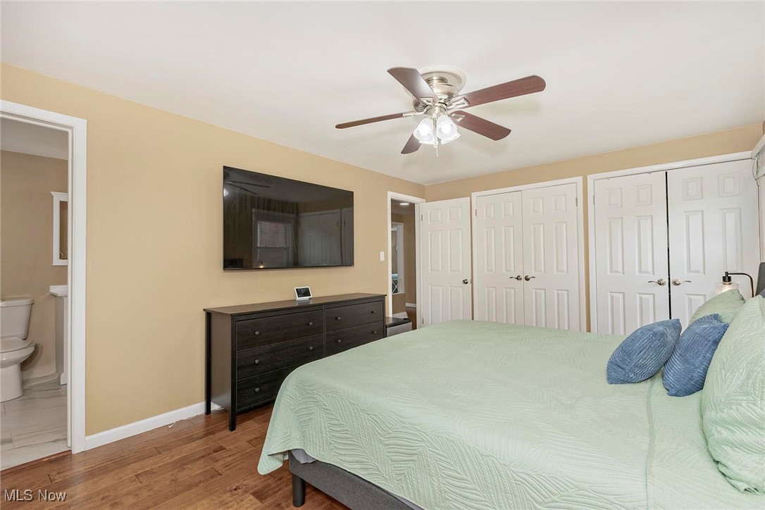 2381 Charney Road Cleveland, OH 44118 - Photo 26 of 47 Bedroom featuring multiple closets, baseboards, ensuite bathroom, wood finished floors, and a ceiling fan