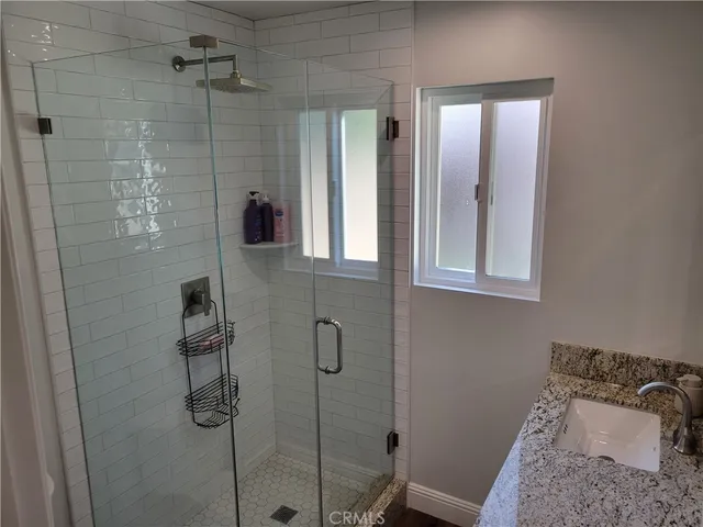 a bathroom with a granite countertop shower a sink and a mirror