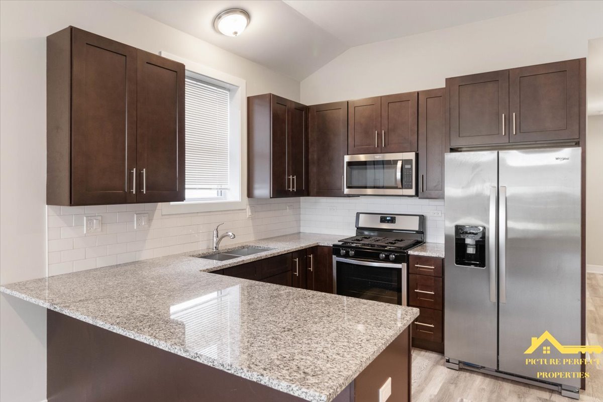 6337 South Ellis Avenue, Unit 3 Chicago, IL 60637 - Photo 2 of 12 a kitchen with stainless steel appliances granite countertop a sink stove and refrigerator
