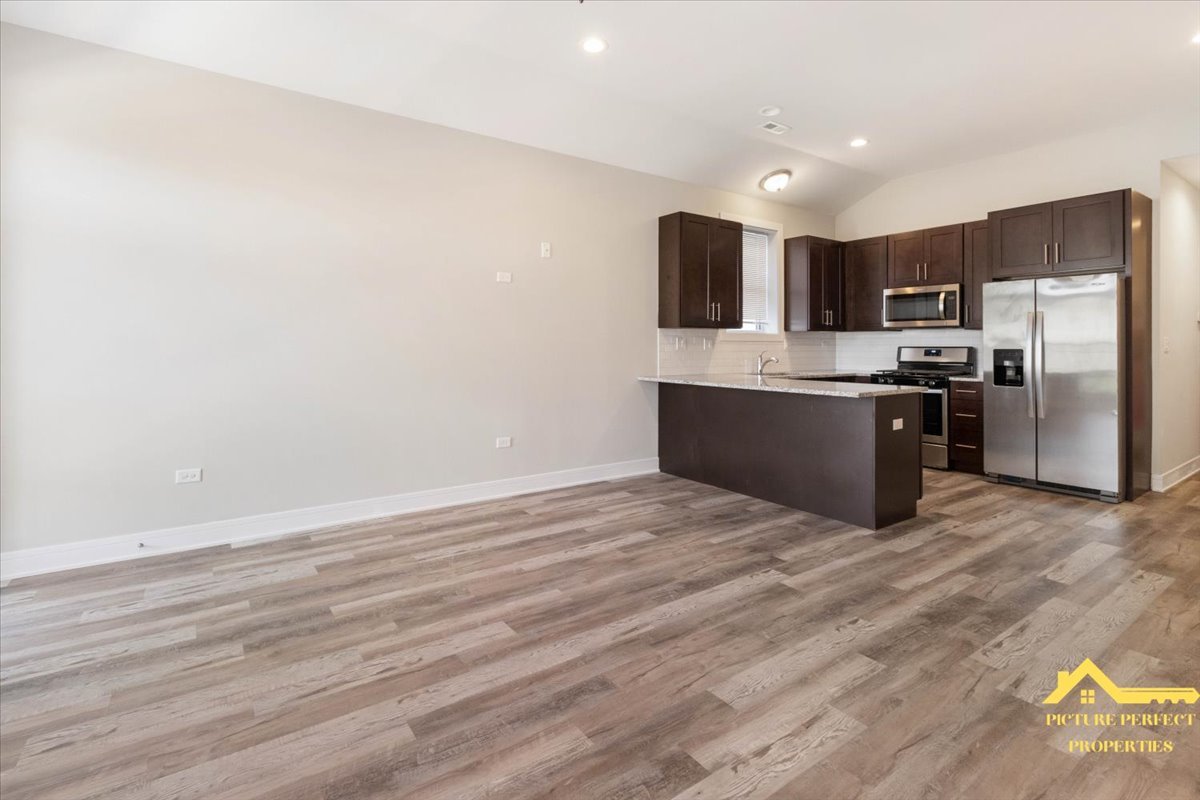 6337 South Ellis Avenue, Unit 3 Chicago, IL 60637 - Photo 3 of 12 a large kitchen with stainless steel appliances a large counter top a stove a microwave and a refrigerator