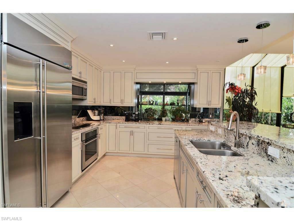 12902 Coco Plum Lane Naples, FL 34119 - Photo 12 of 23 a kitchen with kitchen island a counter top space a sink stainless steel appliances and cabinets