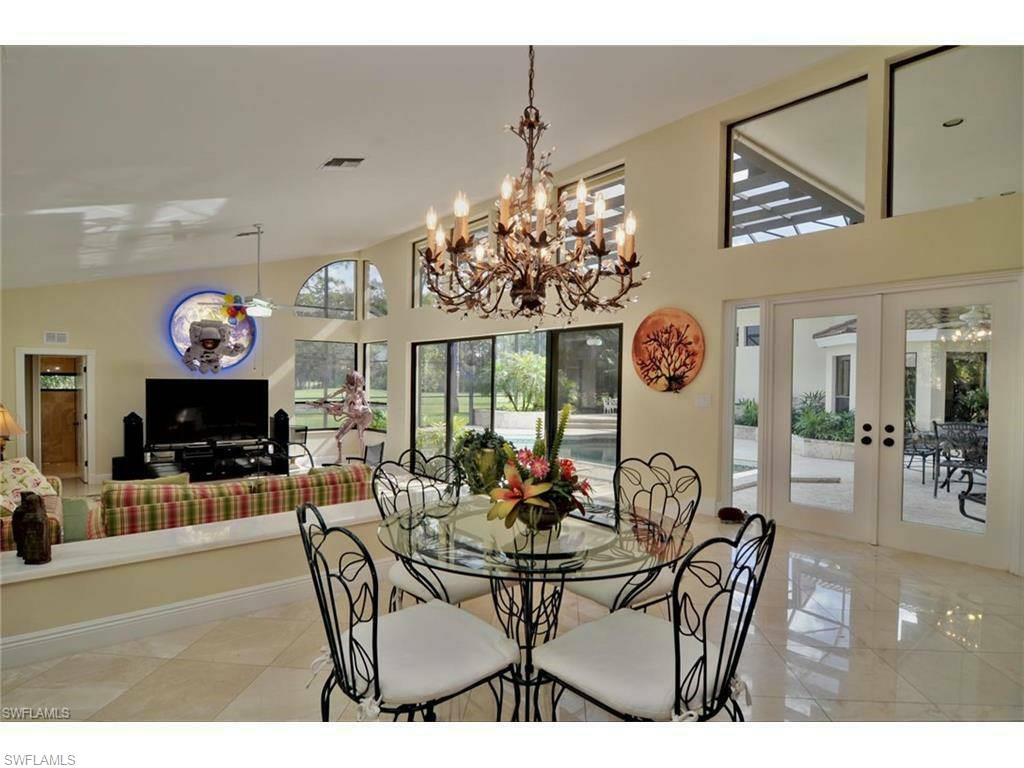 12902 Coco Plum Lane Naples, FL 34119 - Photo 15 of 23 a view of a dining room and kitchen with furniture a chandelier and wooden floor