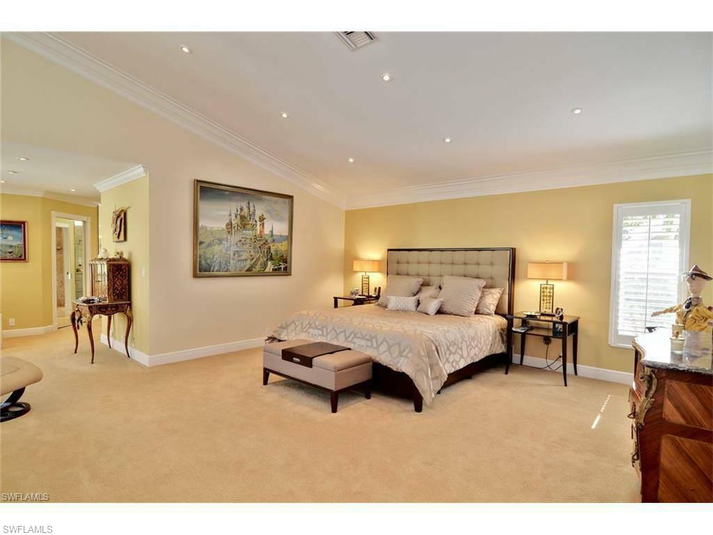 12902 Coco Plum Lane Naples, FL 34119 - Photo 17 of 23 a spacious bedroom with a bed a table and chair