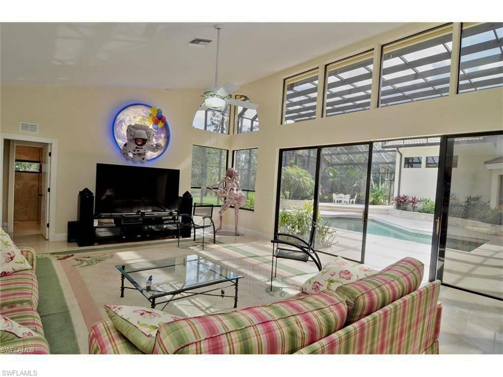 12902 Coco Plum Lane Naples, FL 34119 - Photo 18 of 23 a living room with furniture a flat screen tv and a large window