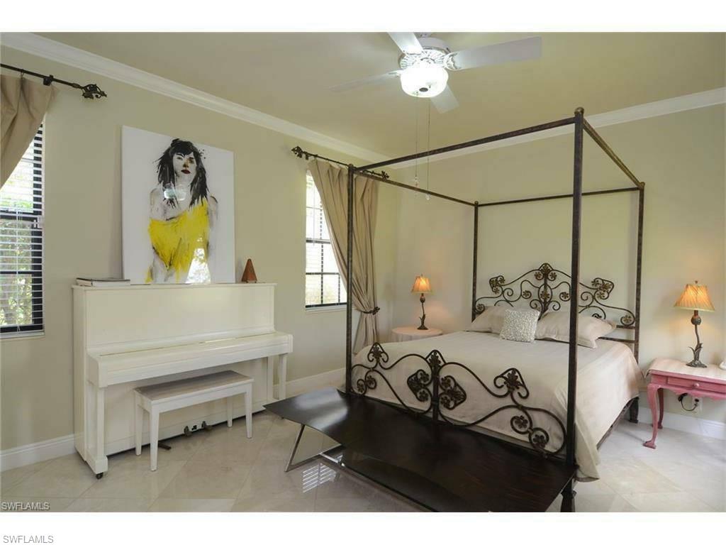 12902 Coco Plum Lane Naples, FL 34119 - Photo 21 of 23 a bedroom with a bed and a chandelier