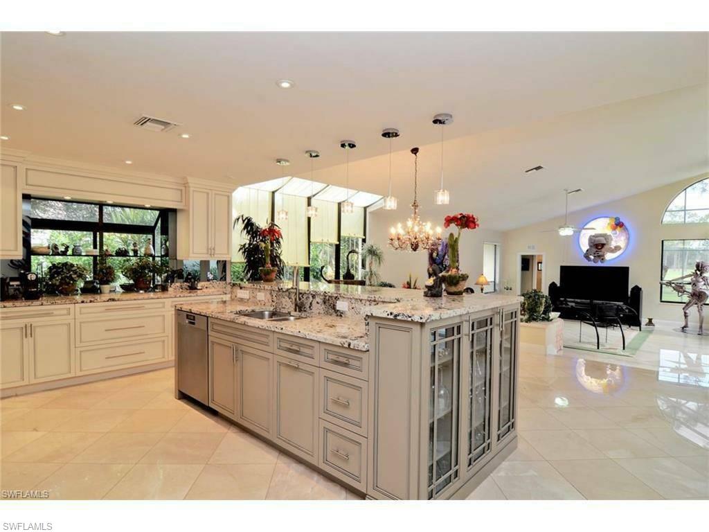 12902 Coco Plum Lane Naples, FL 34119 - Photo 5 of 23 a kitchen with stainless steel appliances kitchen island granite countertop a sink and cabinets