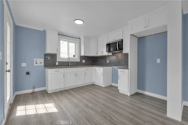a kitchen with granite countertop white cabinets white appliances and a wide window