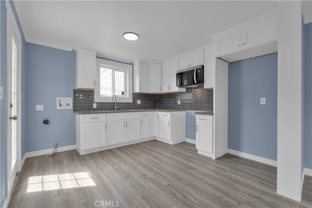 a kitchen with granite countertop white cabinets white appliances and a wide window