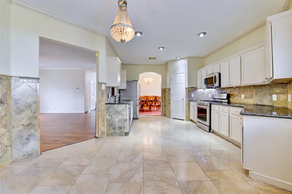 a large kitchen with stainless steel appliances granite countertop a stove refrigerator and cabinets
