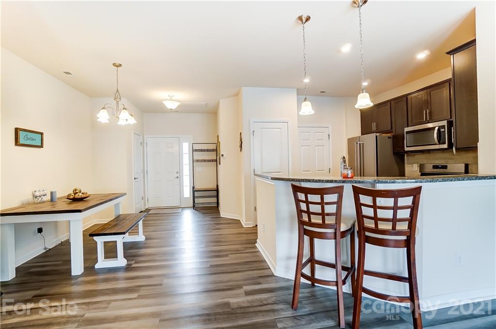 929 Wicawa Road Fort Mill, SC 29708 - Photo 8 of 28 a kitchen with stainless steel appliances kitchen island granite countertop a dining table chairs and a refrigerator