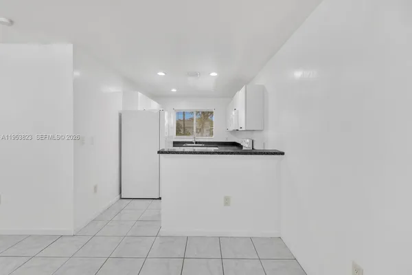 a view of kitchen refrigerator and white cabinets