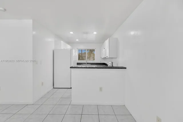 a view of kitchen refrigerator and white cabinets