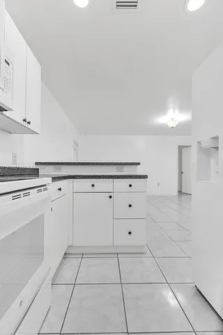 a kitchen with white cabinets and appliances