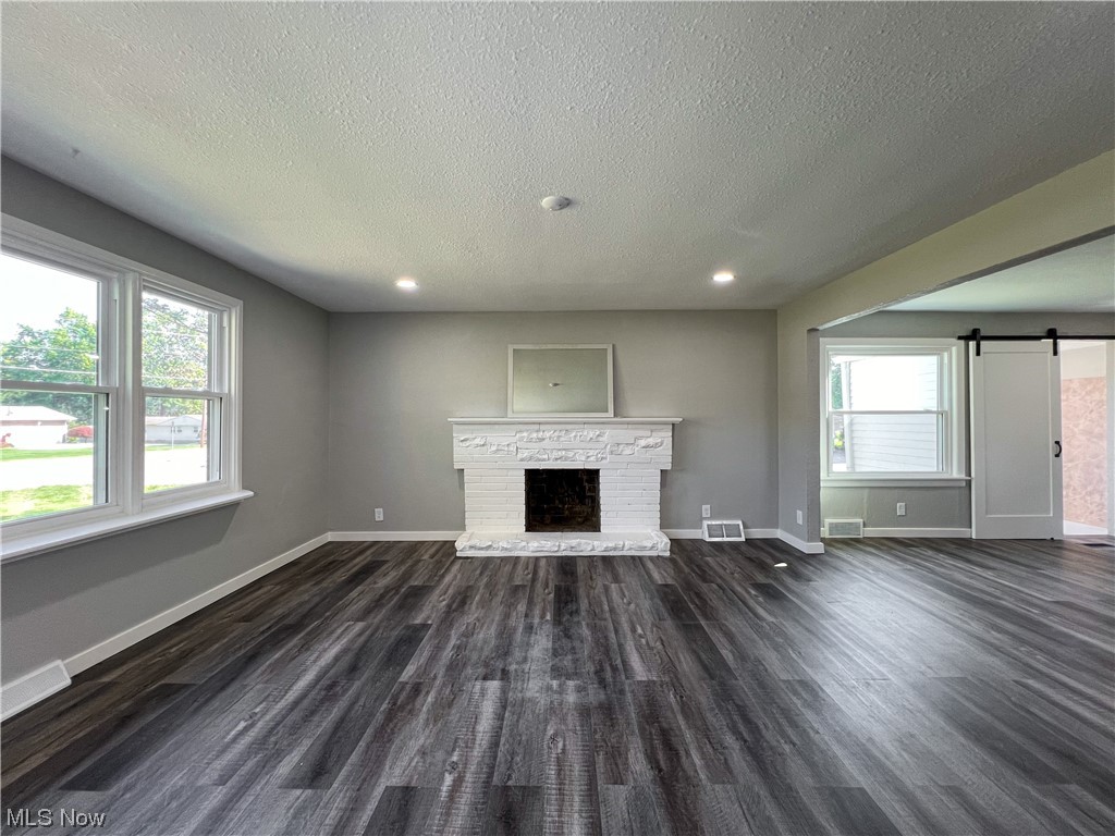 602 West Marshall Road McDonald, OH 44437 - Photo 3 of 19 Unfurnished living room featuring a textured ceiling, a brick fireplace, and dark hardwood floors